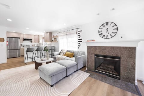 Bright & Airy Open-Plan Living----Cozy gray sofa with mustard accents, round coffee table, and layered rugs. 