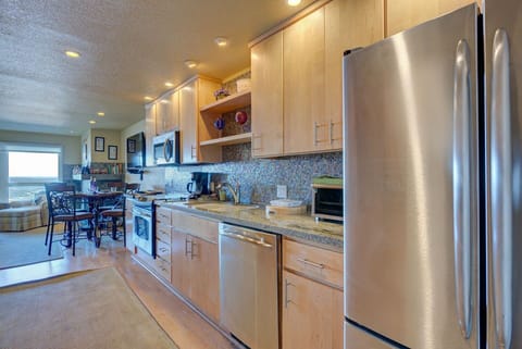 This full kitchen is equipped with modern appliances, including a stainless steel refrigerator and ample counter space, making meal preparation a breeze during your stay.