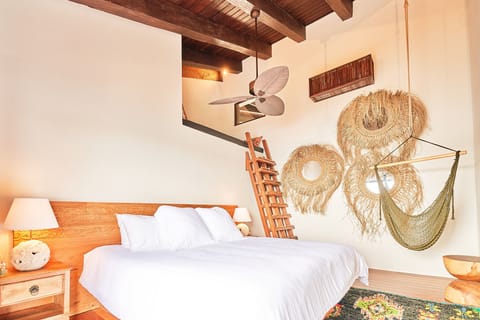 Charming bedroom featuring a cozy loft and artisanal wall hangings.