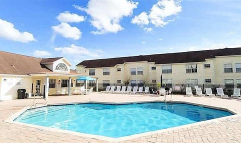 Outdoor pool area with ample lounge seating and a covered patio for relaxation.