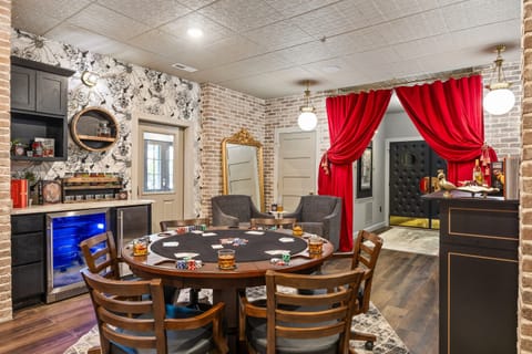 Chic game room with a stylish poker table, vintage-inspired décor, bold red curtains, and a speakeasy vibe. Includes built-in bar and beverage cooler for the ultimate entertaining experience.