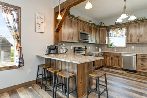 Beautiful farmhouse-style kitchen with warm wood cabinetry, granite counters, and a spacious island with bar seating for four.