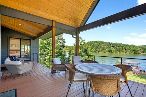 Covered deck, overlooking the lake, with outdoor dining and comfortable seating