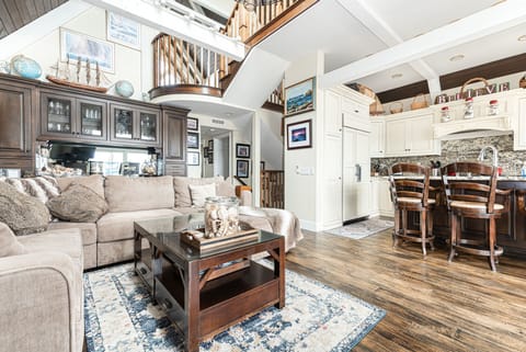 An expansive living room designed for connection and comfort with staircase leading to the upper levels
                