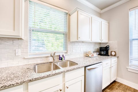 Bright, fully equipped kitchen with granite countertops, double sink, full‑size dishwasher, and a coffee station.
