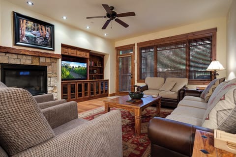 Unwind in your elegant living room featuring a cozy stone fireplace, leather seating, and entertainment center for perfect evening relaxation.