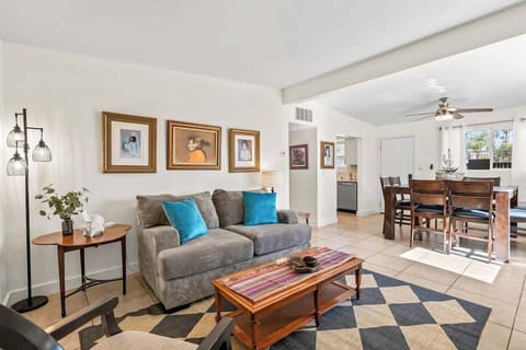 Cozy and artfully decorated living area featuring plush seating, vibrant accent pillows, and charming portraits, perfect for relaxing or enjoying a meal in the adjacent dining space.