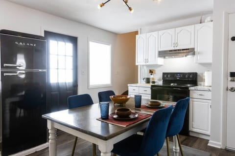 Fully equipped kitchen featuring a refrigerator, sink, stove, microwave, and Instant Pot, along with salt, pepper, olive oil, and essential cooking supplies. A farmhouse table seats four, perfect for shared meals. Handcrafted rustic floating shelves, vint