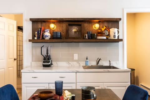 Fully equipped kitchen featuring a refrigerator, sink, stove, microwave, and Instant Pot, along with essential cooking supplies. A farmhouse table seats four, perfect for shared meals. Handcrafted rustic floating shelves, vintage touches, and dimmable lig