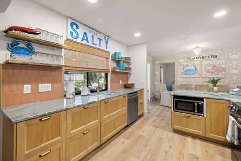 Kitchen: Designed with plenty of prep space, open shelving, and a window that opens to a bar to the pool, this inviting kitchen makes it easy to stay connected while cooking, snacking, or getting ready for a full day of fun.