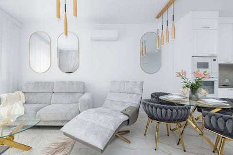 A bright living room with a gray sectional sofa and round mirrors on the wall. The atmosphere is chic and inviting.