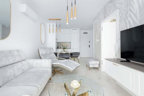 A stylish lounge area featuring a soft sofa and wall-mounted TV. Golden accents add a touch of elegance.