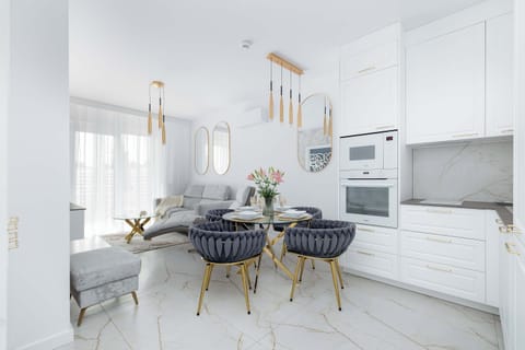 A modern dining area with a round table and plush chairs. The space is illuminated by golden pendant lamps.