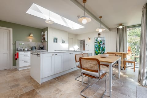 Dining table and modern kitchen with glass doors and green feature wall in St Andrews property.