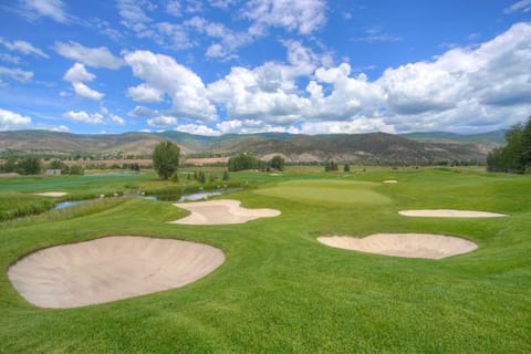 Golf course with sand bunkers and rolling green hills.