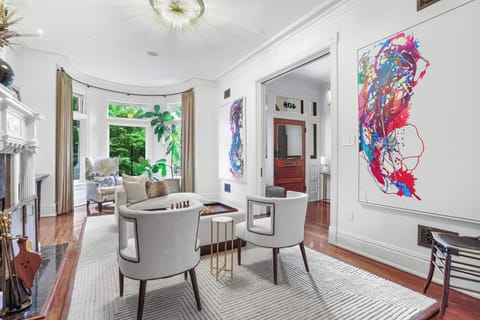 Front living room on the main floor with bay windows, seating area, art, and a decorative firelace. 