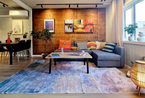 Living space with fireplace, TV, cozy adjustable lighting, and a nice view to the area. Send us a message about the apartment, area, or recommendations for Bergen. Notice the original wooden wall.