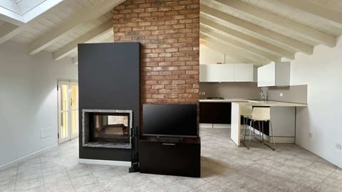 Spacious and bright open-space living room featuring modern design, a ceiling with exposed beams, and a central load-bearing brick wall that divides the space without closing it off