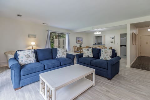 Open and airy living space with cozy navy sofas, a bright coffee table, and seamless flow into the dining area.