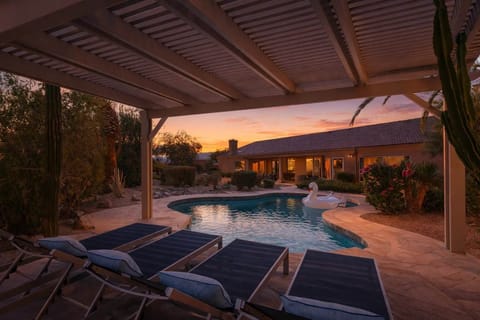 Resort-style backyard with a sparkling pool, gazebo with sun loungers, and covered patio with an outdoor dining table for 8.