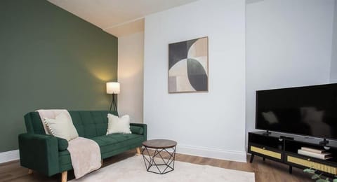 Enjoy this inviting lounge area featuring a plush green sofa, minimalist artwork, and a cozy ambiance