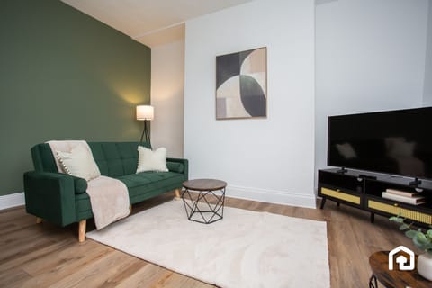 Enjoy this inviting lounge area featuring a plush green sofa, minimalist artwork, and a cozy ambiance