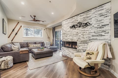Cozy mountain living room with a modern stone fireplace, comfy sectional, and a serene rocking chair. Perfect for relaxing after a day of Park City adventures.