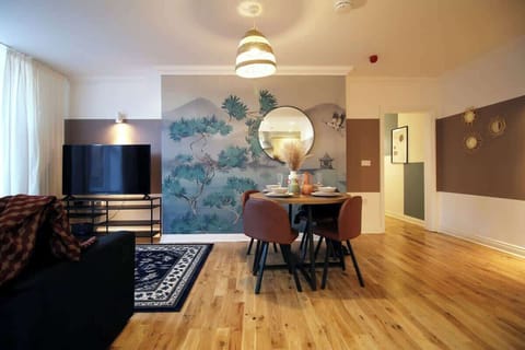 A beautifully styled dining area set within a bright, open-plan space. Featuring elegant décor, feature wall and modern furnishings, it offers a warm, sophisticated setting perfect for relaxed breakfasts, evening meals and social dining.