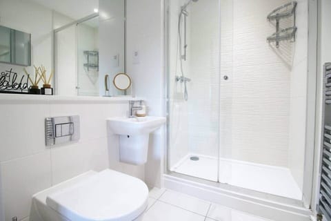 A sleek, modern en-suite featuring a spacious walk-in glass shower, contemporary tiling, 