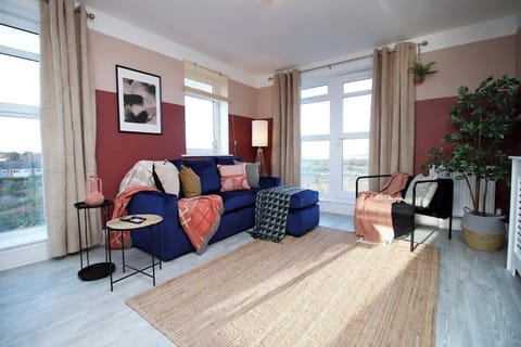 Bright and stylish living space featuring a plush sofa, elegant décor, and large windows that flood the room with natural light—perfect for relaxing after a day exploring.