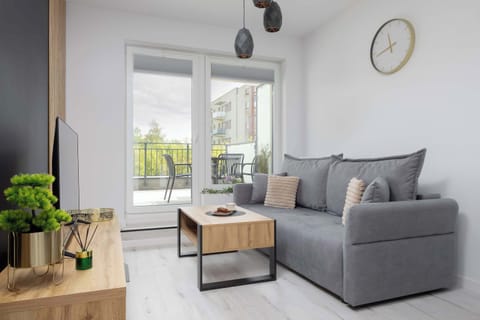 A cozy living room with a large window and balcony access invites you to relax on a comfortable sofa, while enjoying natural light and a peaceful atmosphere.