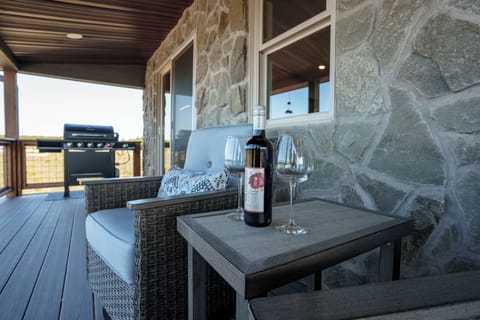 covered deck with 4 comfortable chairs and gas grill.