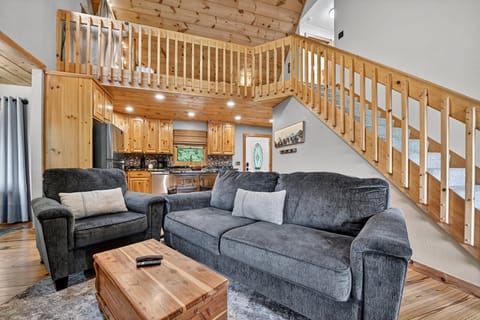 Open-plan living area with comfy sofas and stairs leading to an upstairs loft.