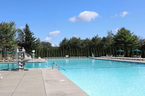 Heated outdoor pool with lounge chairs and umbrellas.