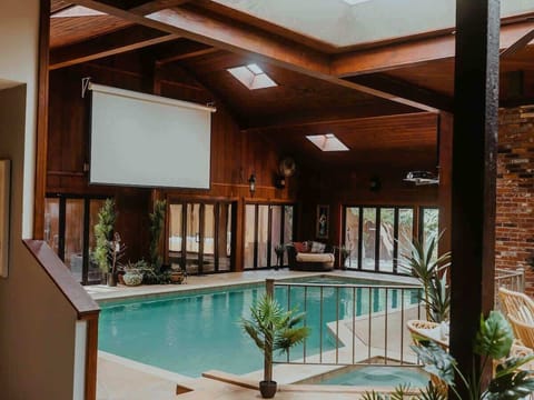 Indoor, climate-controlled hot tub/spa and mineral pool kept at the perfect year-round temperature for swimming. This comfy, designer indoor/outdoor living space boasts a wood burning fireplace, kitchen & giant projector screen for family gatherings.