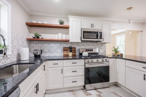 Modern gourmet kitchen featuring sleek appliances, quartz island with two stylish stools, and full cookware. A perfect blend of elegance and function for cooking or casual dining.