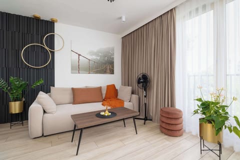 The living room with large windows and a soft neutral sofa invites you to relax in a bright and elegant atmosphere.