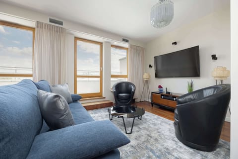 Spacious living room with modern sofa, armchair, and TV.