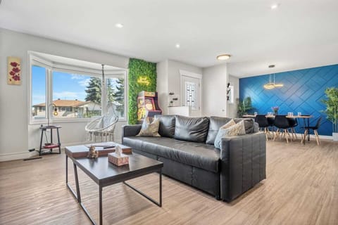 Enjoy this airy living space with a cozy seating area, plush leather couch, and retro arcade machine. Perfect for family gatherings, this open-concept room flows into a modern dining area for ease.