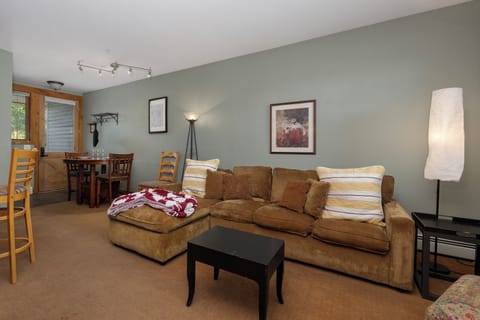 Sink into this cozy living room at Kicking Horse Maverick 5-203 where soft lighting and warm furnishings create your perfect retreat after mountain adventures.