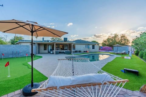 Backyard play day with the pool and mini-putt green—cool off in the water, then take turns lining up putts on the bright turf while everyone lounges nearby.