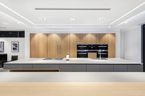 Sleek modern kitchen featuring expansive prep island, built-in ovens, and refined lighting