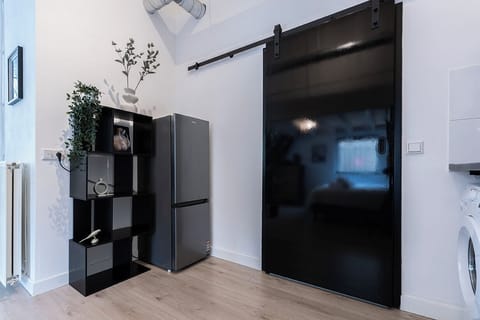 Modern fridge and decorative shelving beside a sleek black sliding door in Bed en Koffie, Tilburg Centrum.
