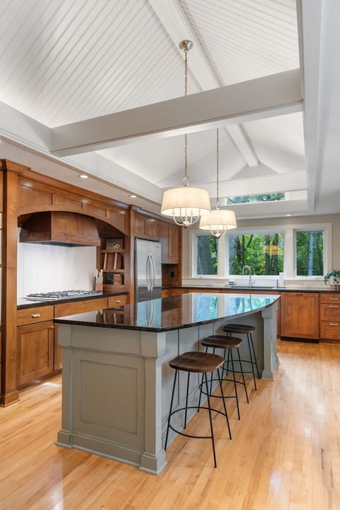Your gourmet kitchen beckons with rich wood cabinets, granite island, and soaring beamed ceilings that create an airy, elegant cooking space.