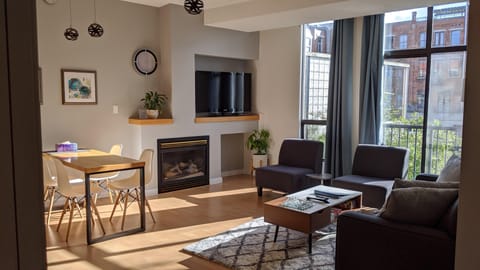 Welcome to the Inner Harbour Retreat! Sunlit open-concept living room featuring a gas fireplace, dining area, and direct access to outdoor views.