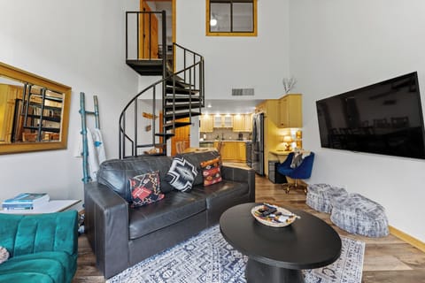 Living area with a mounted TV, wood-burning fireplace, sleeper sofa, and wine fridge.