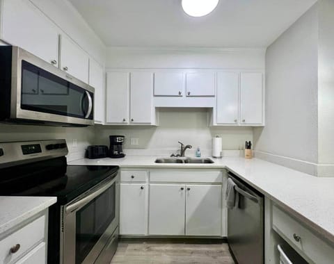 This fully equipped kitchen features stainless steel appliances, a large counter with seating, and a cozy dining nook framed by natural light. Whether you’re cooking a full meal or enjoying takeout, this space is perfect for gathering and dining in.
