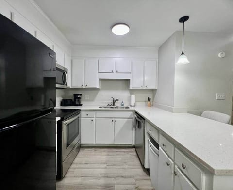This fully equipped kitchen features stainless steel appliances, a large counter with seating, and a cozy dining nook framed by natural light. Whether you’re cooking a full meal or enjoying takeout, this space is perfect for gathering and dining in.
