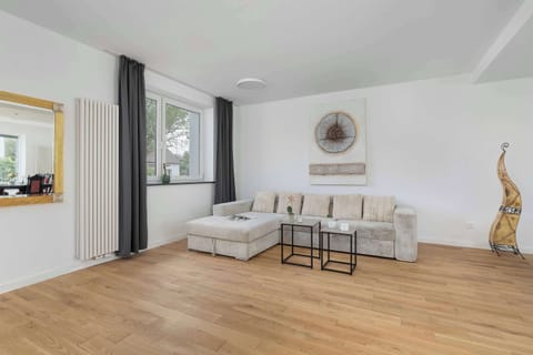 Bright and spacious living room with large windows and stylish wooden flooring.