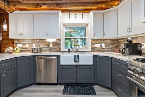 Elegant farmhouse sink, stone backsplash, and premium appliances add modern luxury to this classic log cabin kitchen.